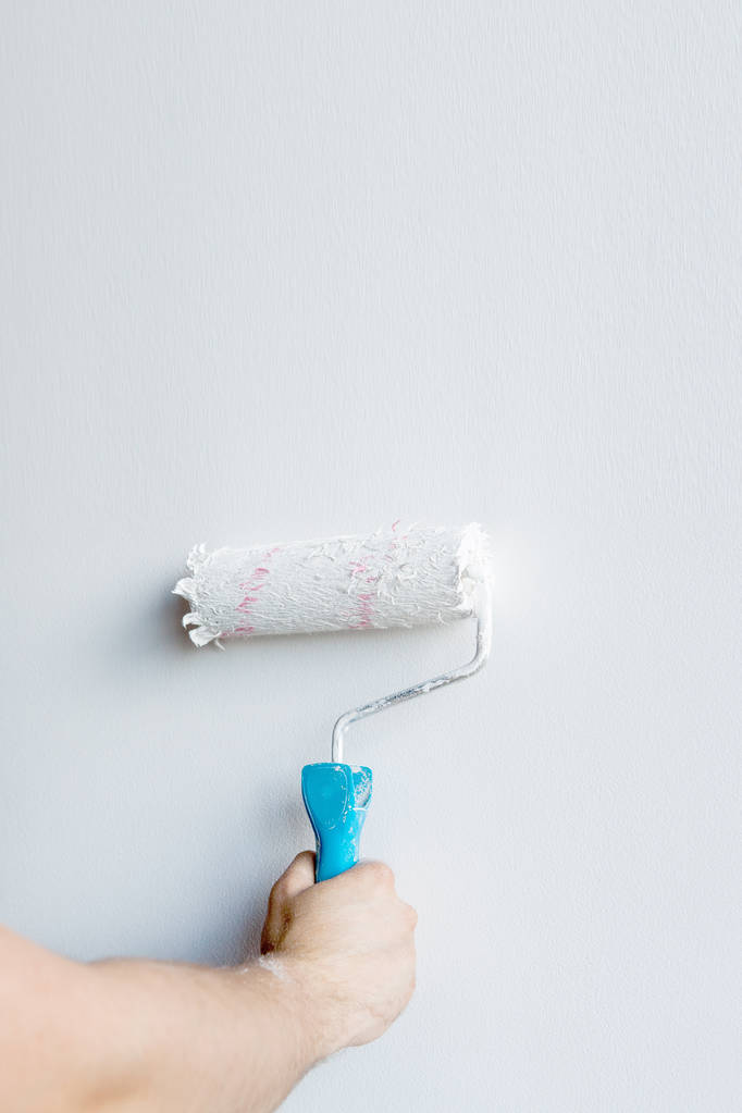 Mano de mujer sosteniendo un rodillo de pintura aislado sobre un fondo blanco
 - Foto, Imagen