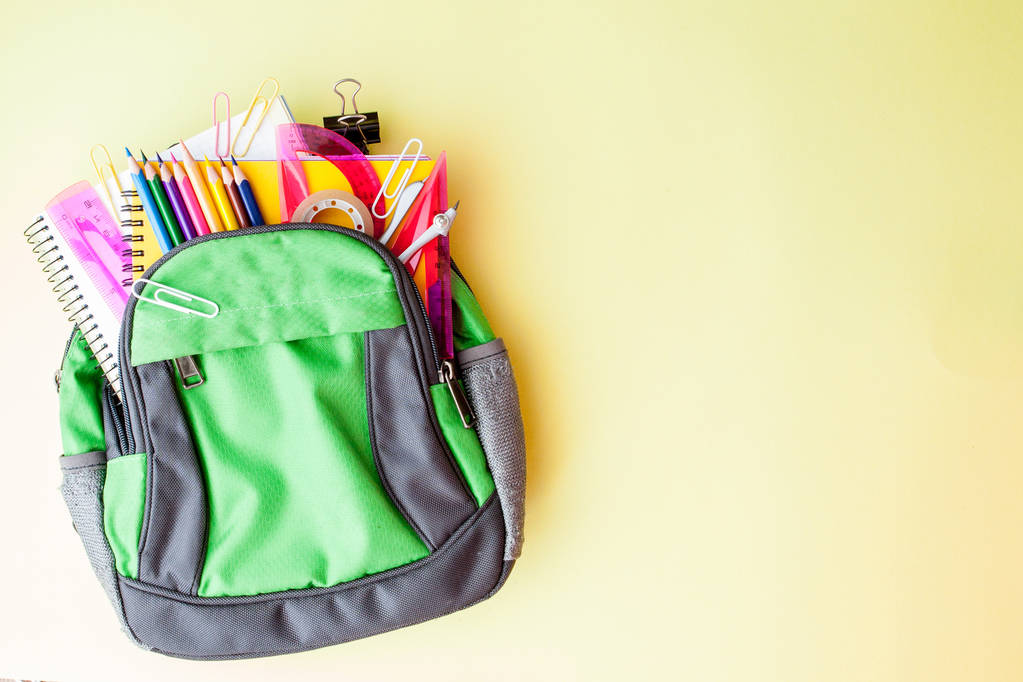 flache Liegekomposition mit Rucksack und Schulpapier auf gelbem Hintergrund - Foto, Bild