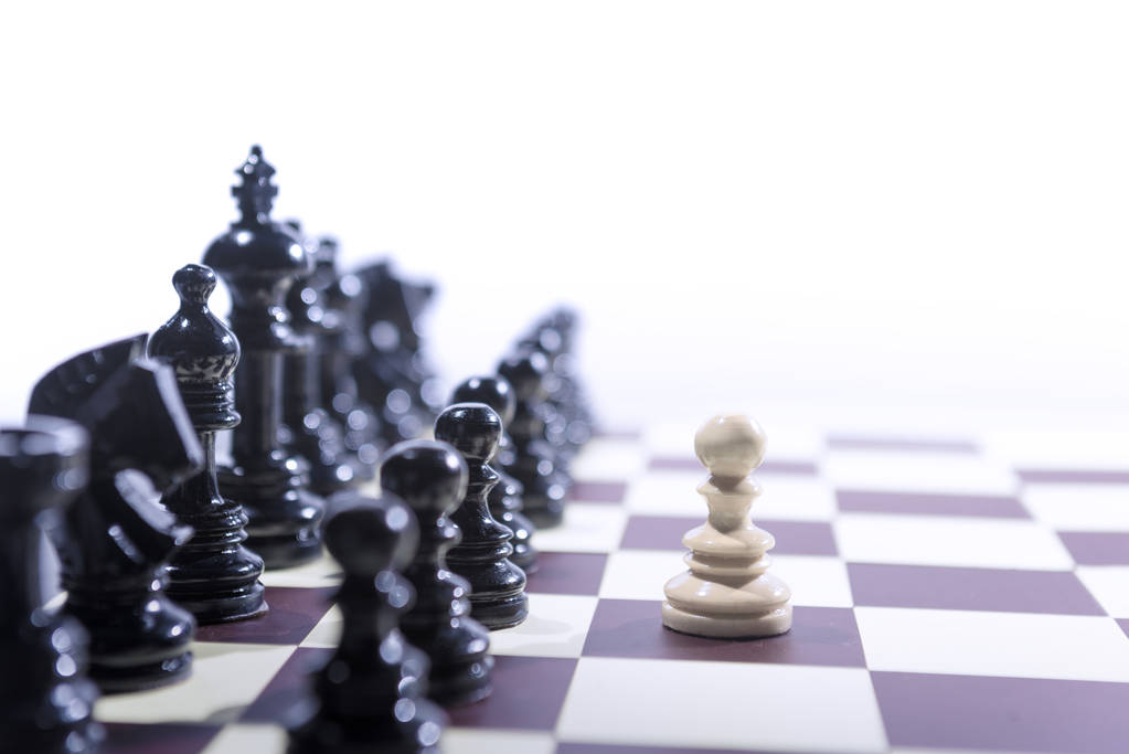 Pieza de ajedrez de peón blanco de pie delante de todo el grupo de negro
 - Foto, imagen