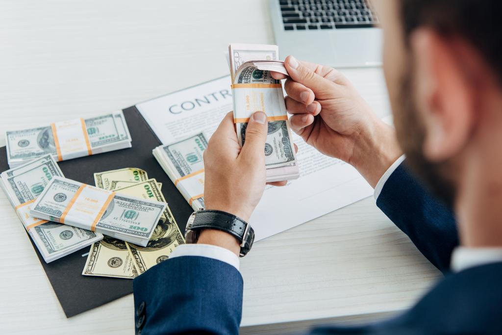 вибірковий фокус бізнесмена, який тримає доларові банкноти поблизу контракту в офісі
  - Фото, зображення