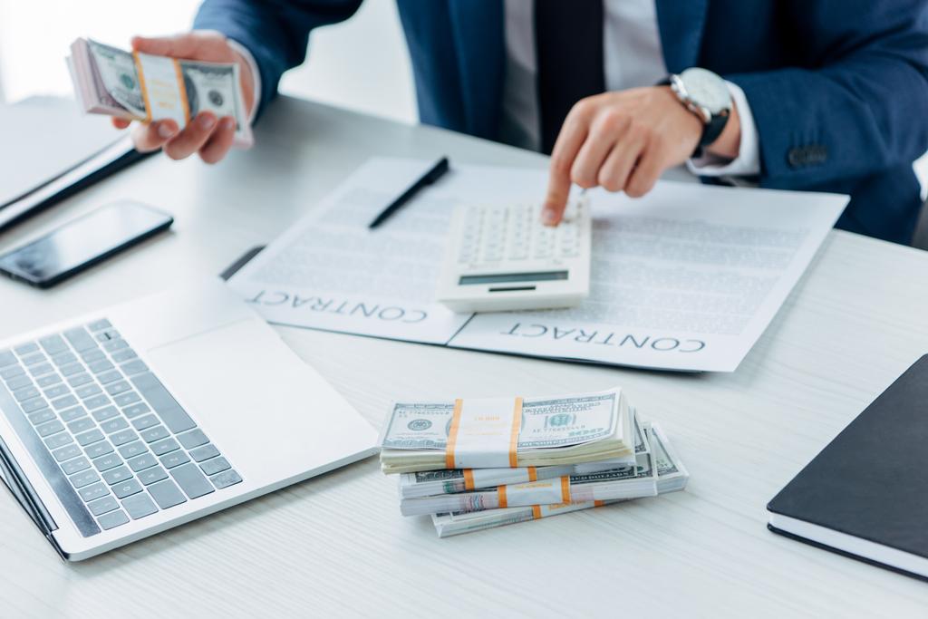 обрізаний вид бізнесмена, використовуючи калькулятор і тримаючи гроші поблизу контракту
  - Фото, зображення