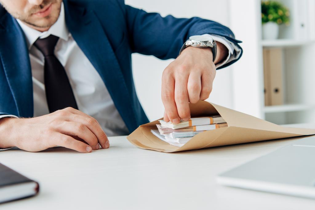 обрізаний вид бізнесмена, дивлячись на конверт з грошима
  - Фото, зображення