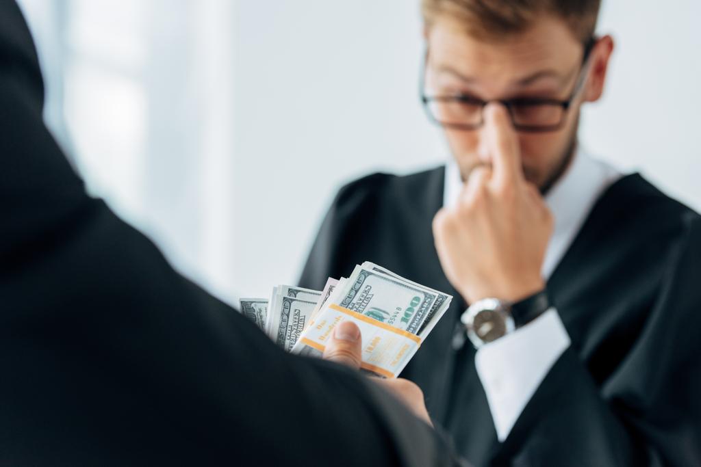 селективный фокус человека, держащего деньги возле судьи в очках
  - Фото, изображение