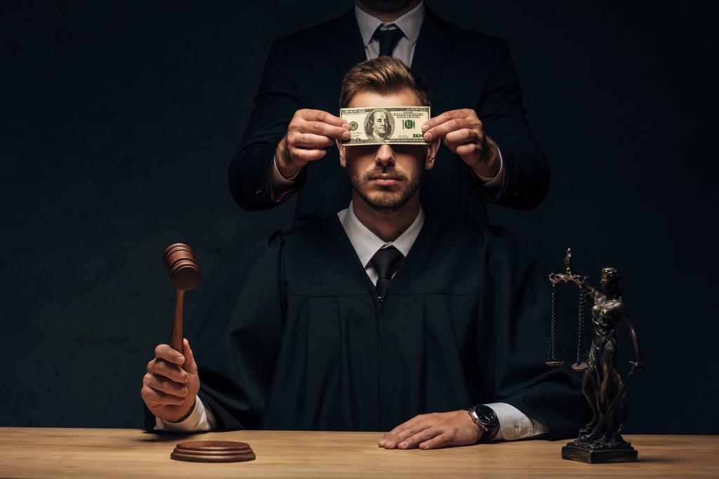 Ausgeschnittene Ansicht eines Mannes, der steht und das Gesicht des Richters mit Schmiergeld auf schwarz bedeckt  - Foto, Bild