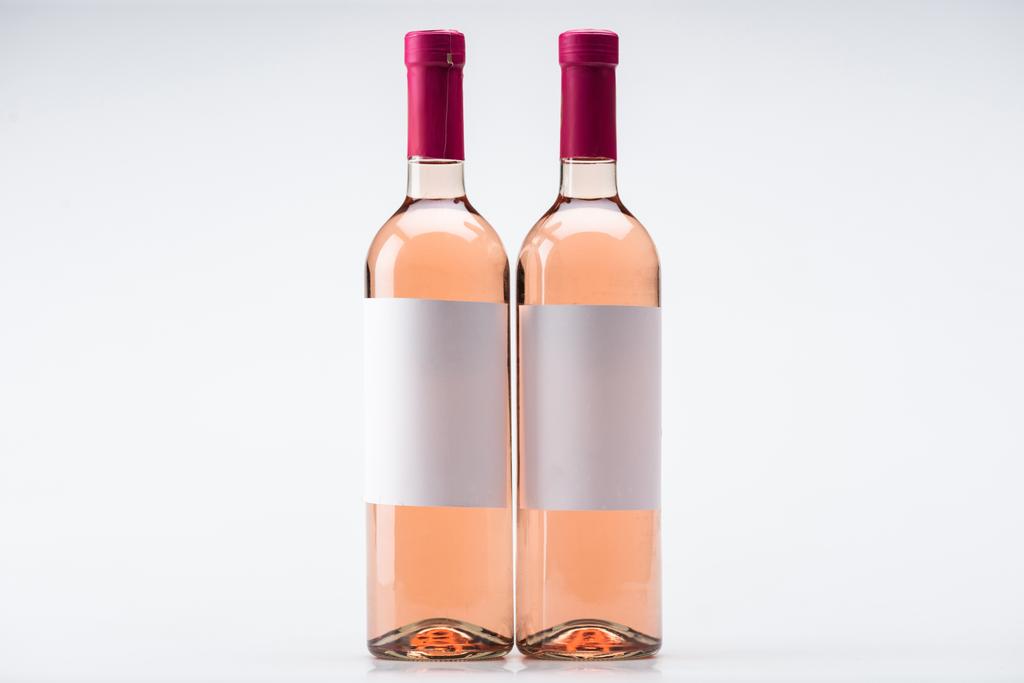 dvě lahve z růžového vína s prázdnými štítky na bílém pozadí - Fotografie, Obrázek