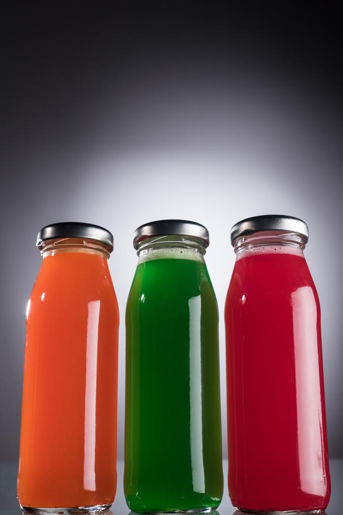 vista de ángulo bajo de botellas de vidrio con líquido multicolor sobre fondo oscuro con luz de fondo
 - Foto, Imagen