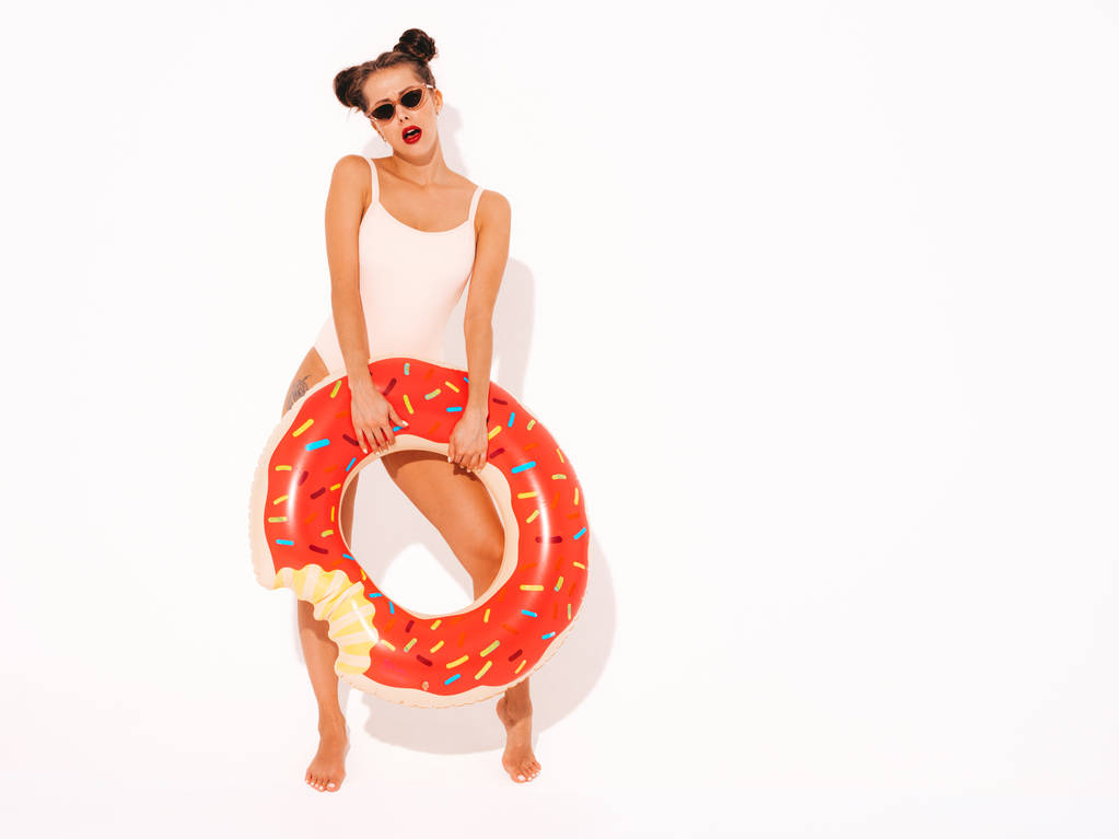 Молодая красивая сексуальная улыбчивая женщина-хипстер с красными губами в летнем купальнике купальный костюм с пончиком lilo inflatable mattress.female going crazy.Funny модель изолирована
  - Фото, изображение