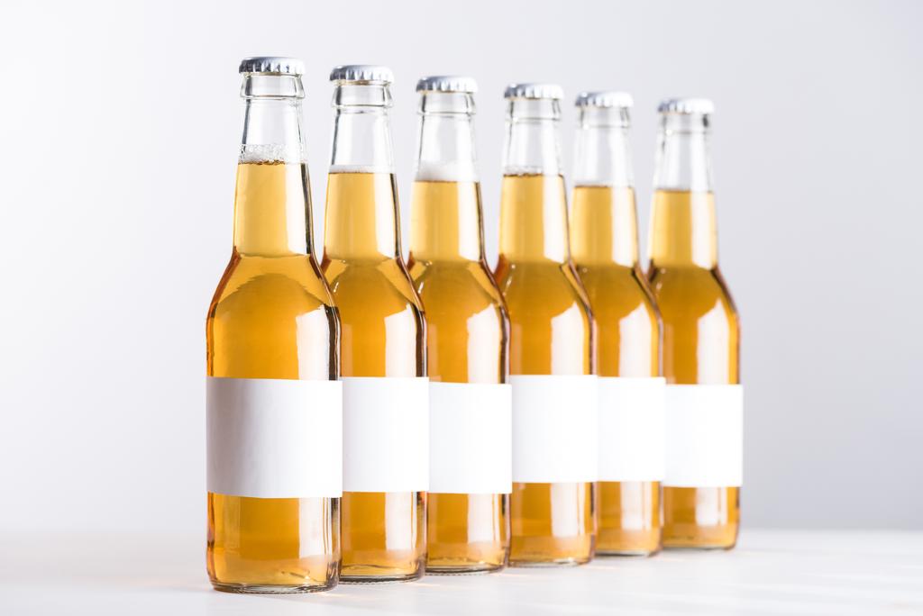 γυάλινες φιάλες μπύρας με κενές λευκές ετικέτες απομονωμένες σε γκρι - Φωτογραφία, εικόνα