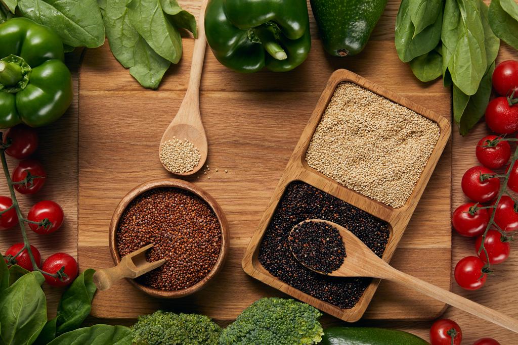 vue du dessus du quinoa blanc, rouge et noir dans des bols près de légumes mûrs et cuillères sur planche à découper
 - Photo, image