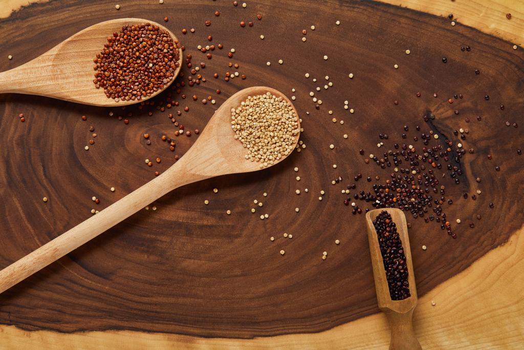 Widok z góry białego, czerwonego i czarnego quinoa w drewnianej łyżce na beżowo-brązowym stole - Zdjęcie, obraz