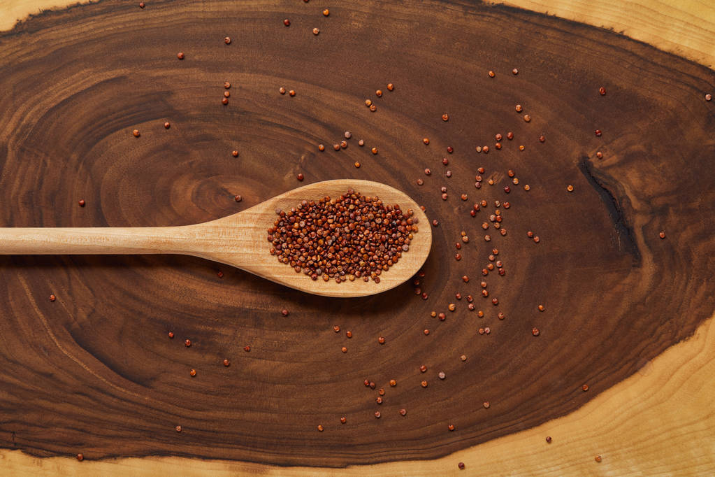 top view of red quinoa in wooden spoon on beige and brown table - Photo, Image