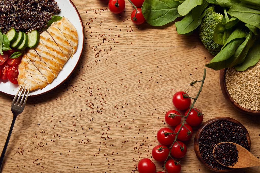 Widok z góry gotowanej quinoa z grillowaną pierś z kurczaka i warzywami na białej płycie na drewnianym stole - Zdjęcie, obraz