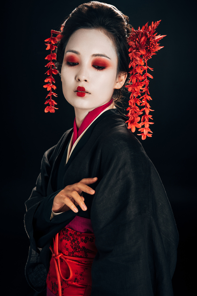 gyönyörű gésa fekete és piros kimonó virágok és a haj néz elszigetelt fekete - Fotó, kép