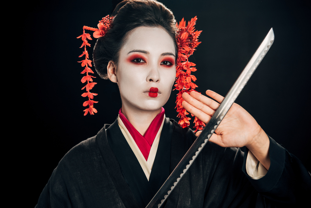 bella geisha in kimono nero con fiori rossi in capelli che tengono katana affilata isolata su nero
 - Foto, immagini