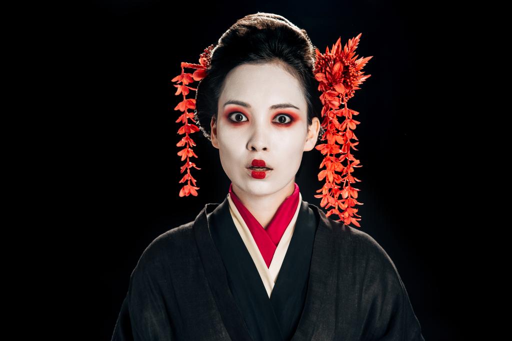 döbbent szép gésa fekete és piros kimonó és virágok haját izolált fekete - Fotó, kép