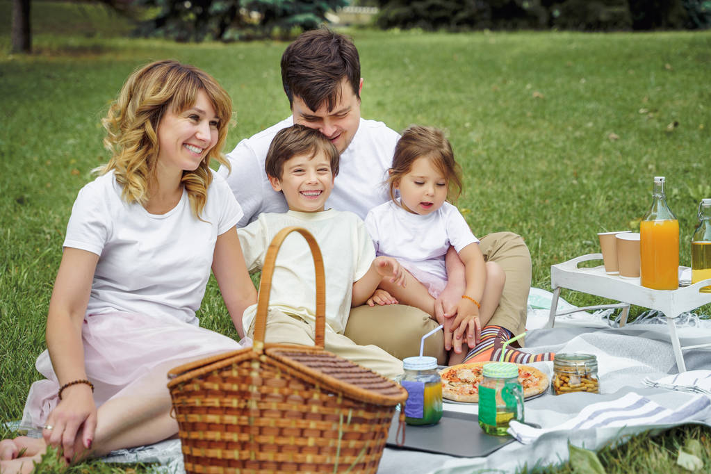 Famiglia felice con bambini che riposano sull'erba durante un picnic. Felicità e armonia nella vita familiare
. - Foto, immagini