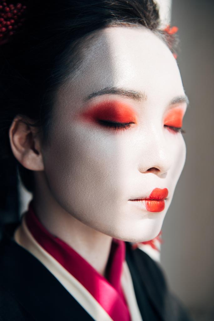 retrato de bela gueixa com maquiagem vermelha e branca com olhos fechados à luz do sol
 - Foto, Imagem