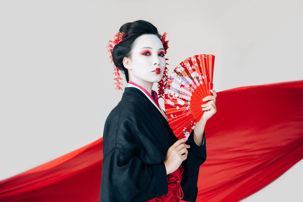 bella geisha in kimono nero con ventaglio a mano e panno rosso su sfondo isolato su bianco
 - Foto, immagini
