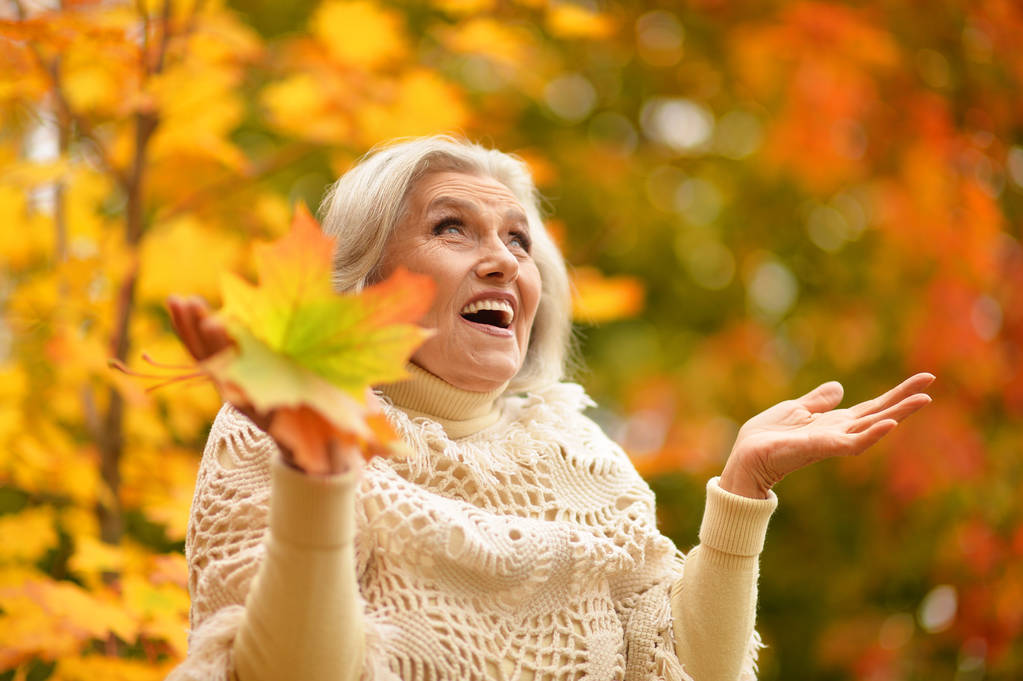 Счастливая пожилая женщина в осеннем парке
 - Фото, изображение