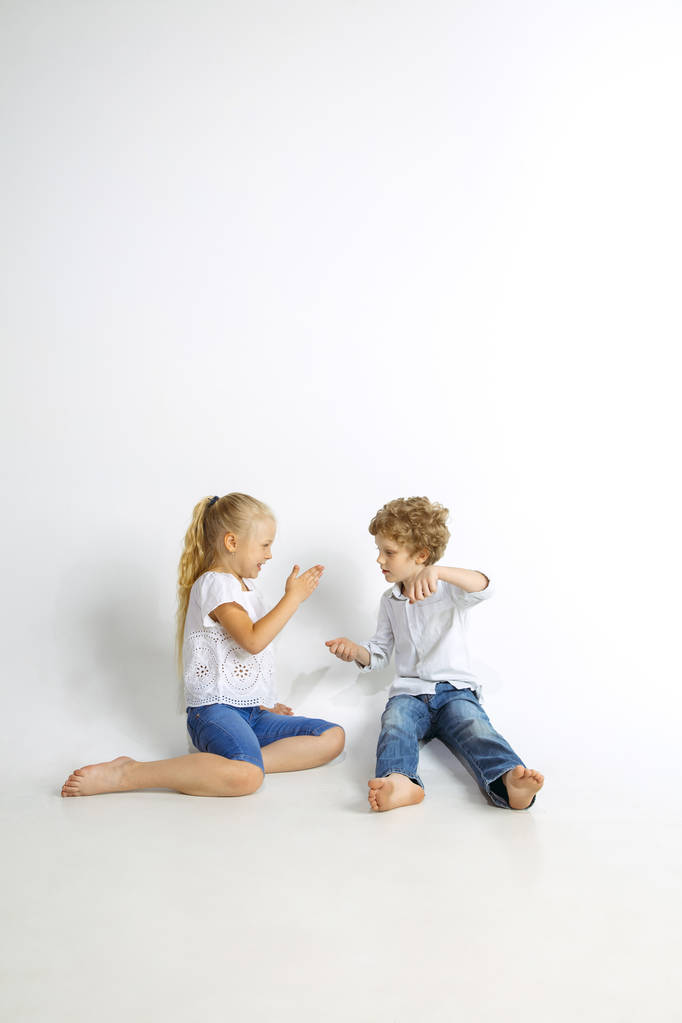Αγόρι και κορίτσι παίζουν μαζί σε λευκό στούντιο φόντο - Φωτογραφία, εικόνα