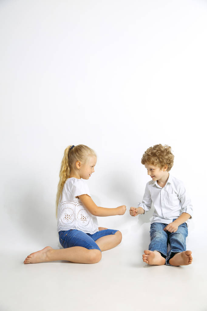 Αγόρι και κορίτσι παίζουν μαζί σε λευκό στούντιο φόντο - Φωτογραφία, εικόνα