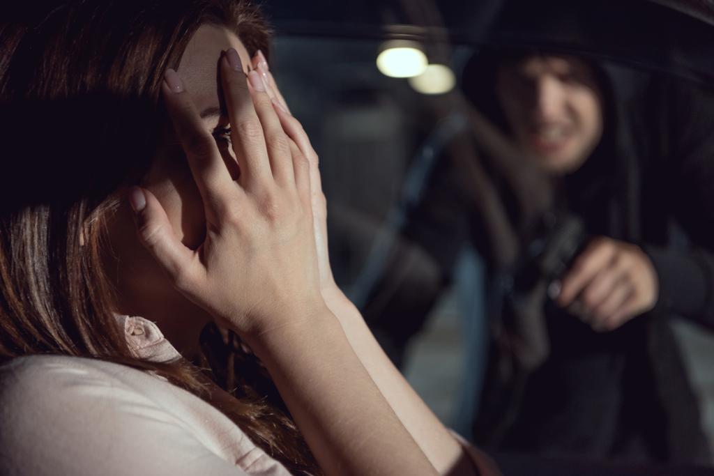 злодій вказує пістолет на жінку, сидячи в машині вночі
 - Фото, зображення