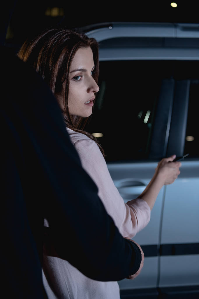 złodziej atakuje kobietę z tyłu w pobliżu samochodu w nocy - Zdjęcie, obraz