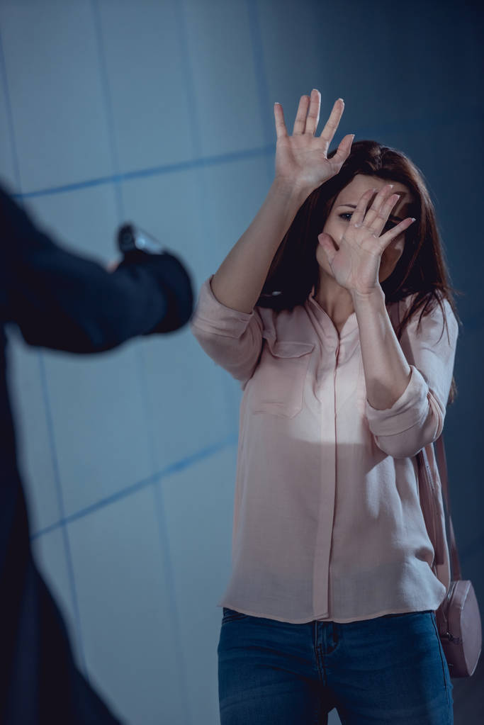 pistolet celowanie na kobietę pokrywającą twarz z rękami - Zdjęcie, obraz
