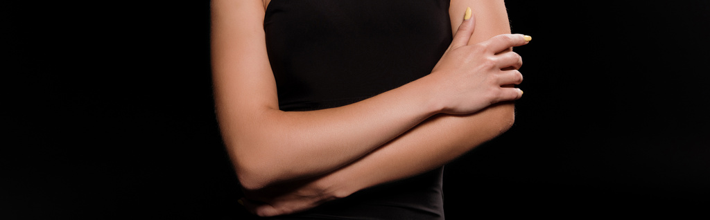 黒で隔離された十字架の腕を持つ若い女性のパノラマショット  - 写真・画像