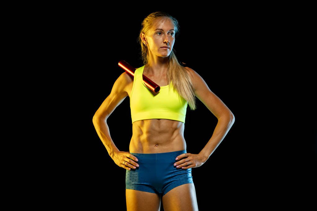 Professionele vrouwelijke estafette racer training op zwarte studio achtergrond in neon licht - Foto, afbeelding