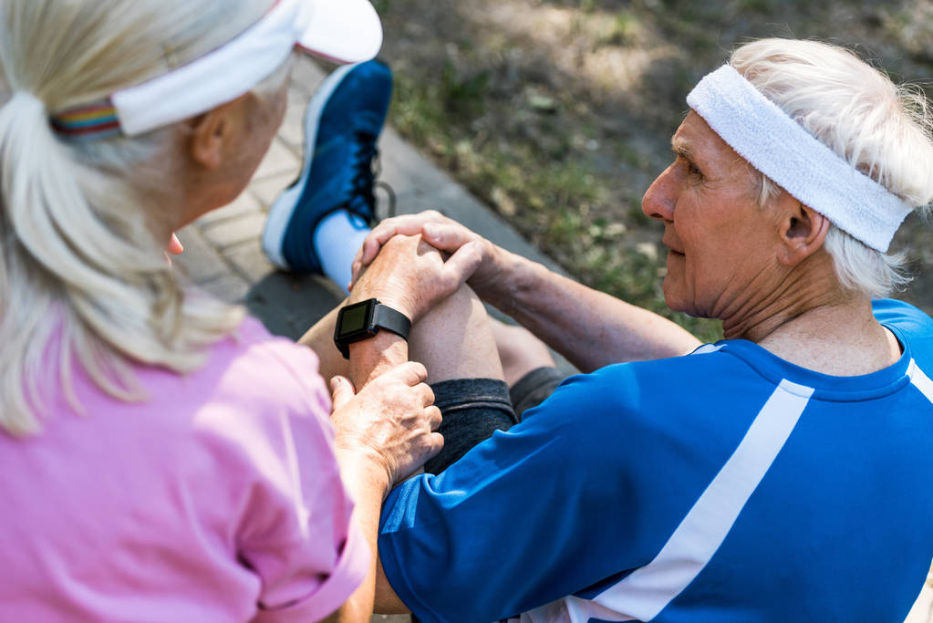 selektywnej ostrości starszych kobiet w Cap siedzi w pobliżu emerytowanego człowieka dotykając kolana  - Zdjęcie, obraz