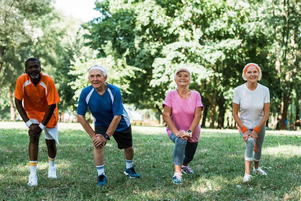 ευτυχισμένοι ηλικιωμένοι και πολυπολιτισμικοί άνθρωποι που κάνουν τέντωμα άσκηση στο γρασίδι  - Φωτογραφία, εικόνα