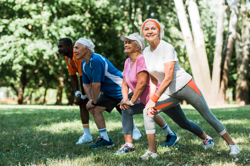 селективное внимание счастливых пожилых и мультикультурных людей, делающих упражнения на растяжку на траве
  - Фото, изображение