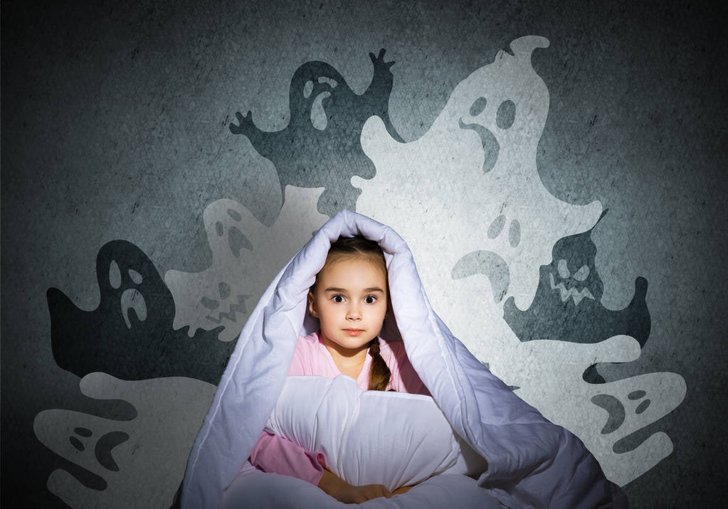 Scared girl with pillow hiding under blanket. Startled kid sitting in his bed at home. Little girl afraid of dark. Covered child not sleep at night. Fearful girl in pajamas and imaginary monsters. - Photo, Image