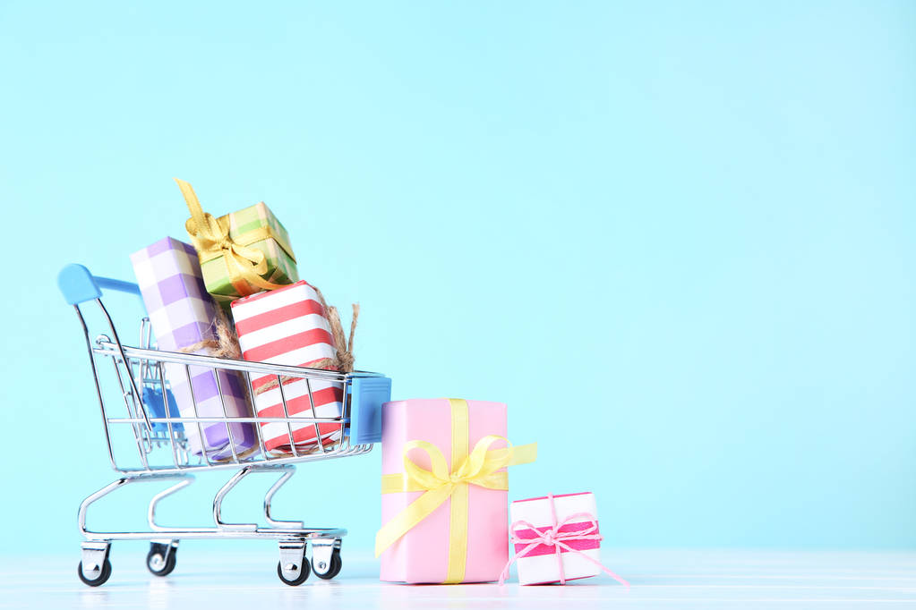 Carrinho de compras pequeno com caixas de presente no fundo azul
 - Foto, Imagem