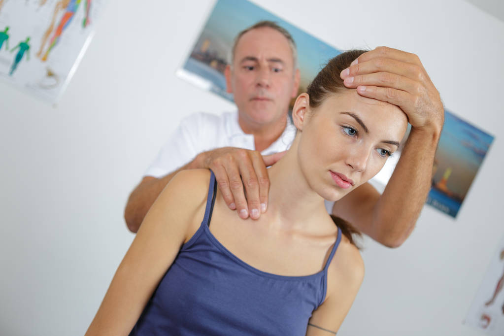 Fisioterapista che fa un massaggio al collo alle pazienti in clinica
 - Foto, immagini