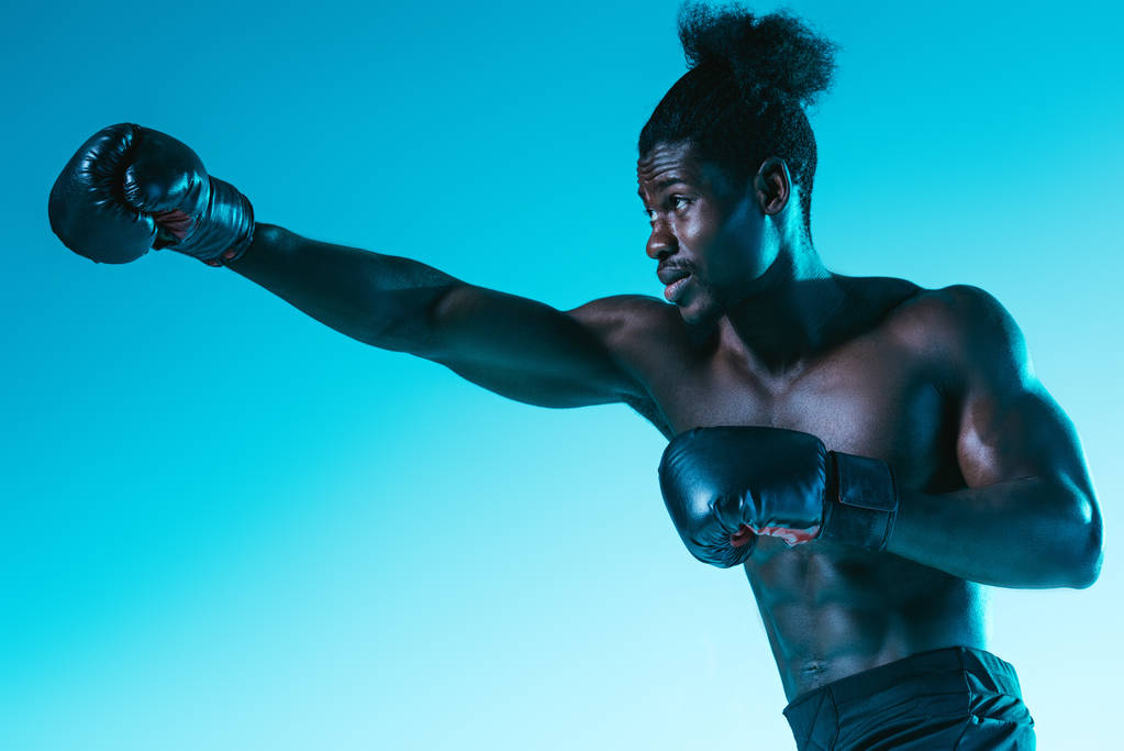 deportista africano confiado en el entrenamiento de guantes de boxeo sobre fondo azul
 - Foto, Imagen