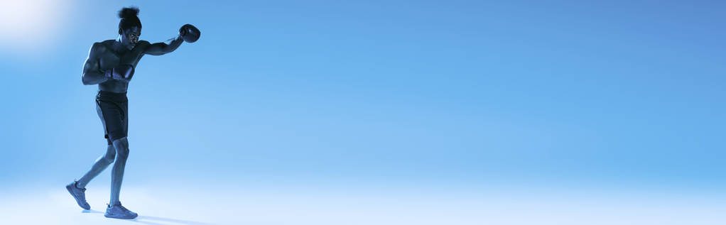 panoramatický záběr na širý africký americký sportovec box na modrém pozadí - Fotografie, Obrázek