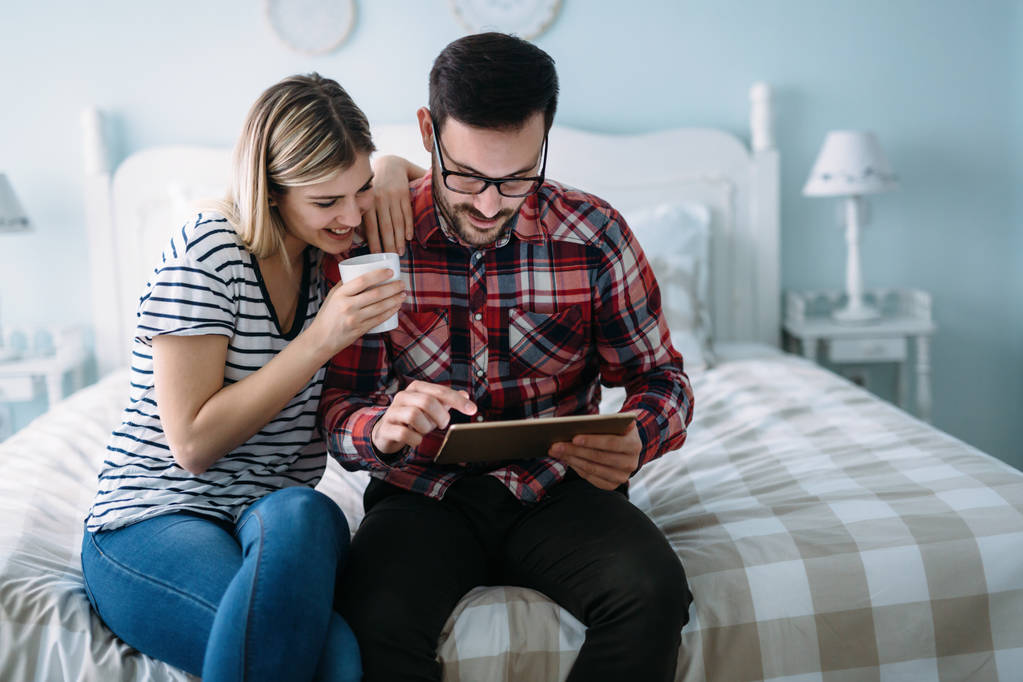 Молодая счастливая пара с помощью цифрового планшета в спальне
 - Фото, изображение