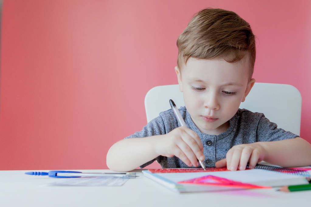 宿題を作る家でかわいい子供の男の子の肖像画。カラフルな鉛筆で書く小さな集中した子供、屋内。小学校と教育。文字と数字を書くことを学ぶ子供 - 写真・画像