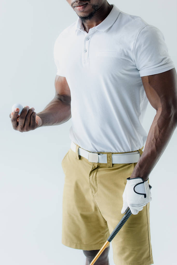 Teilansicht eines afrikanisch-amerikanischen Golfspielers, der Ball isoliert auf grau hält - Foto, Bild