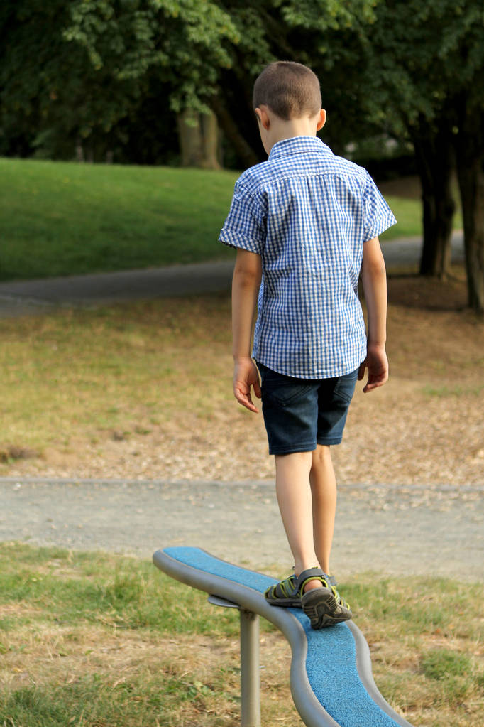 menino estudante em shorts caminha em um projétil jogo de esportes horizontais em um playground em um parque no verão, coordenação de treinamento e equilíbrio corporal
 - Foto, Imagem