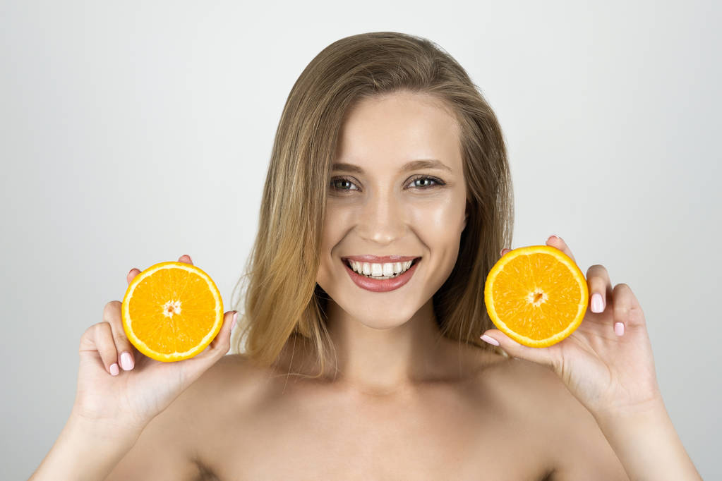 joven hermosa rubia mujer sosteniendo naranjas en sus manos buscando feliz aislado fondo blanco
 - Foto, Imagen