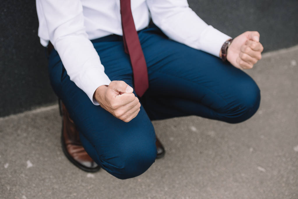 visão cortada de empresário sentado com punhos apertados
  - Foto, Imagem
