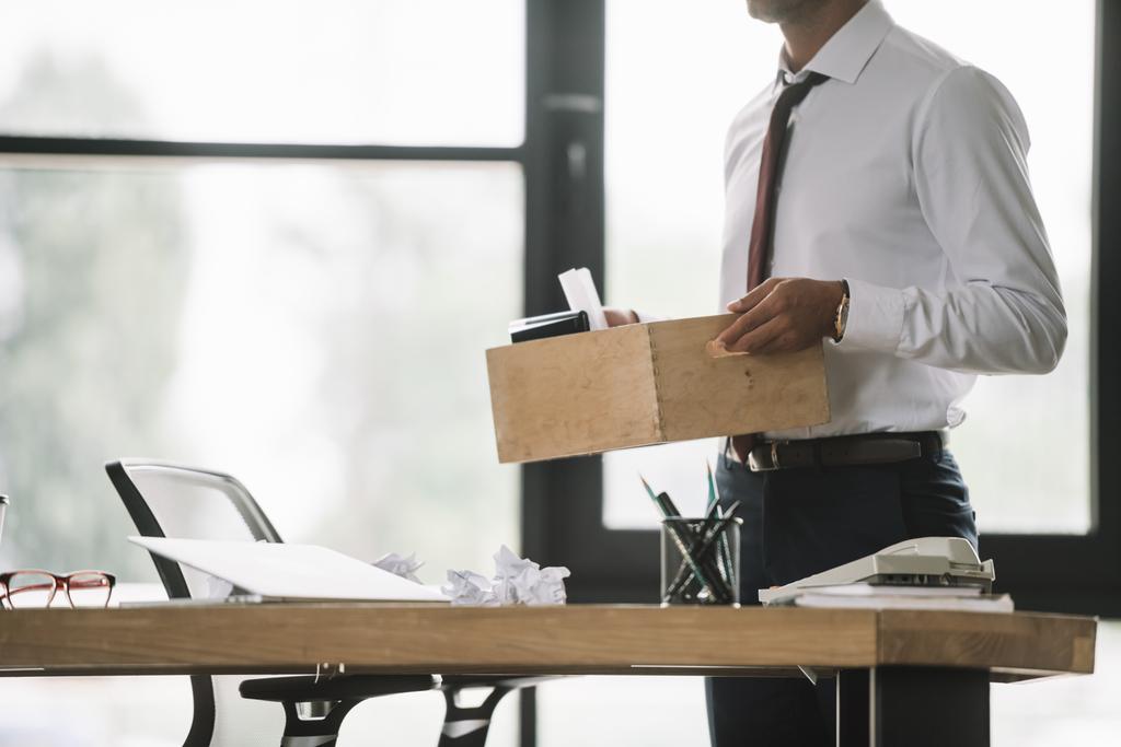 обрезанный вид уволенного бизнесмена с деревянной коробкой в современном офисе
  - Фото, изображение