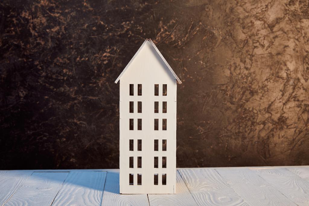 Model domu na drewnianym stole w pobliżu brązowej teksturowanej ścianie, koncepcja nieruchomości - Zdjęcie, obraz