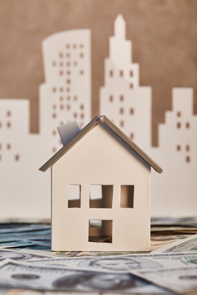 modelo de casa em notas de dólar com papel branco cidade em segundo plano, conceito imobiliário
 - Foto, Imagem