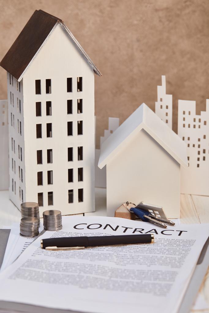 моделі будинків на білому дерев'яному столі з контрактом, ключами та монетами, концепція нерухомості
 - Фото, зображення