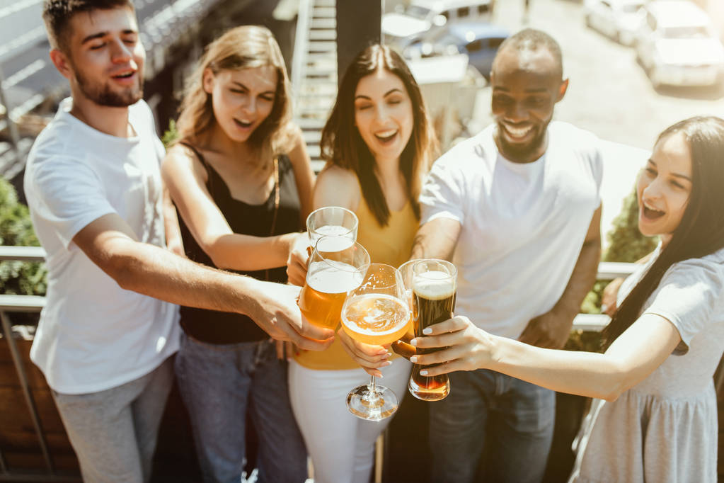 Jovem grupo de amigos bebendo cerveja e comemorando juntos
 - Foto, Imagem