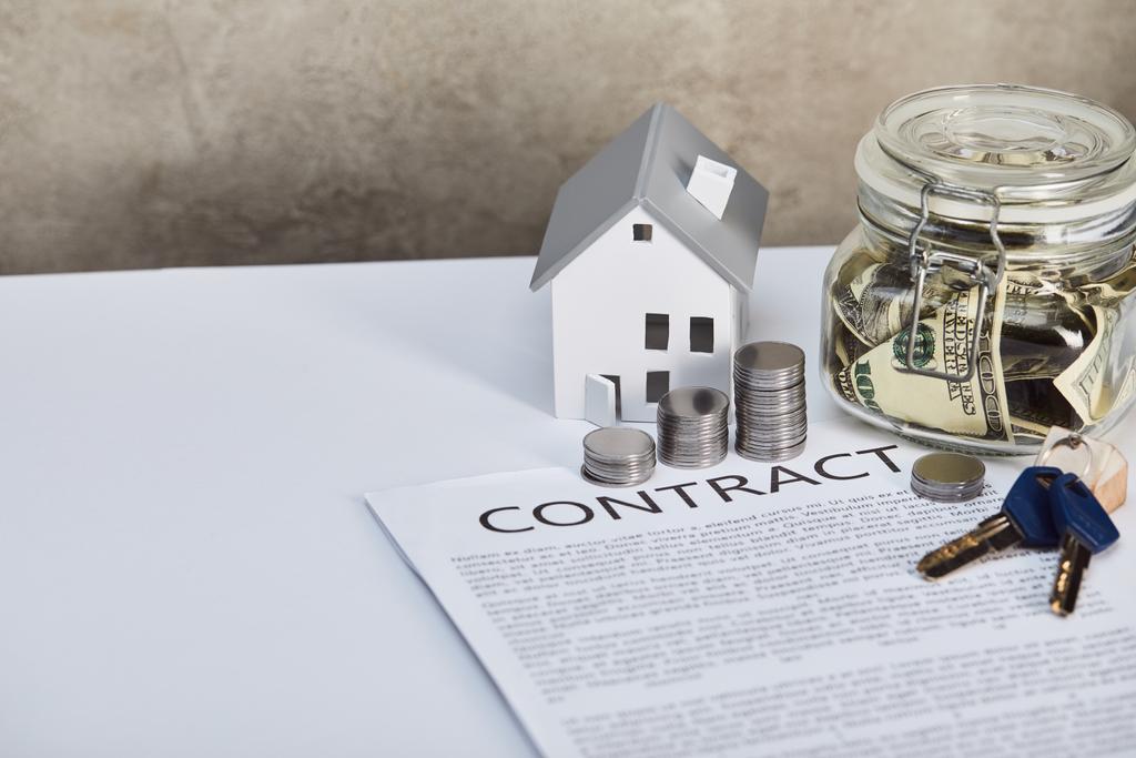 modèle de maison sur table blanche avec des pièces d'argent, clés, contrat et tirelire, concept immobilier
 - Photo, image
